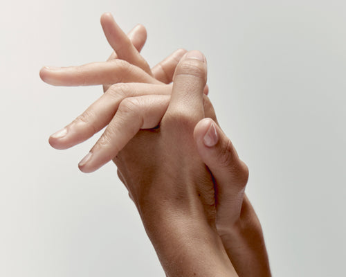 Close-up of two hands with light skin against a plain background