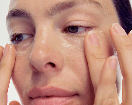 Woman applying cream under her eyes
