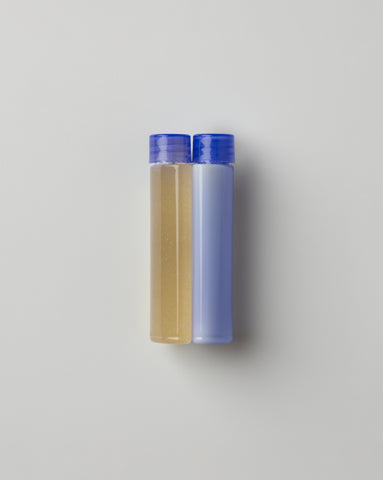 Two small refill pods with purple caps placed side by side on a light background with black borders on the sides. The left pod contains Live probiotic Serum while the right pod contains the Activating Creme