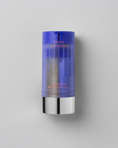 Emma Lewisham Supernatural Blemish Face Serum in translucent purple bottle with silver base displayed against gray background with visible serum inside the container.