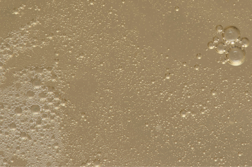 Close-up of beige liquid with bubbles on a textured background
